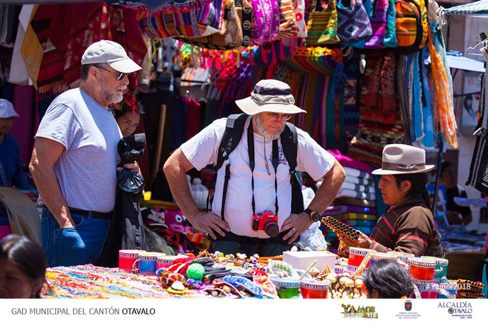Visitors shopping among colorful textiles at Otavalo Plaza de Ponchos.